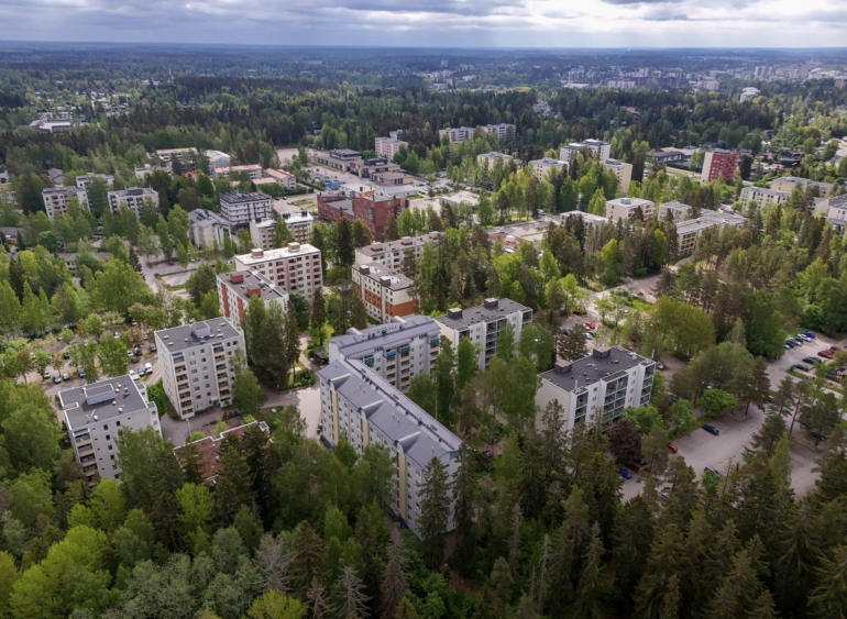 Ilmakuva asuinalueesta, jossa on kerrostaloja ja runsaasti vehreyttä.
