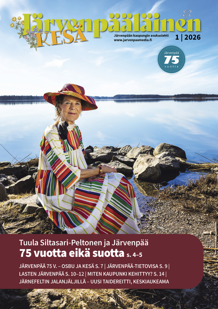 Värikkääseen hameeseen pukeutunut nainen istuu kalliolla järven rannalla. Taustalla näkyy tyyni järvi ja sininen taivas. Lehtikuvan otsikko on 'Järvenpääläinen KESÄ 1 2026' ja siinä mainitaan 'Järvenpää 75 vuotta'.