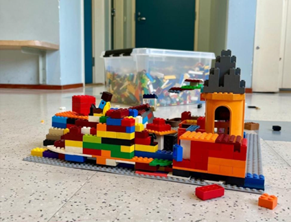 Lattialla on värikkäitä legoja, joista on tehty jonkinlainen linna.