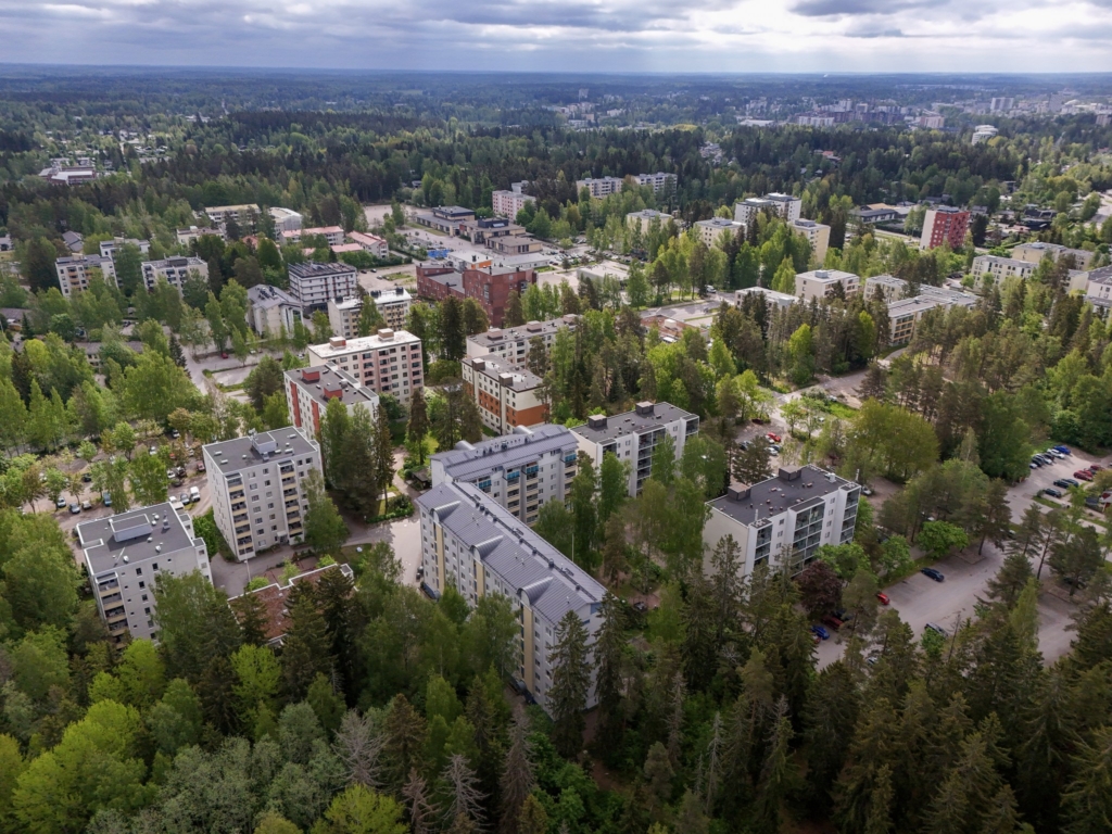Ilmakuva asuinalueesta, jossa on kerrostaloja ja runsaasti vehreyttä.