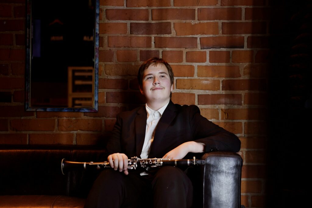 Joonatan Henriksson istumassa sohvalla sylissään klarinettinsa.