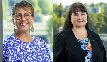 Kaksi naista kuvassa. Toisella naisella on silmälasit ja lyhyt tukka, toisella pitkä tummat hiukset.