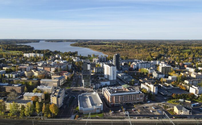 Ilmakuva kaupungista, jossa on moderneja rakennuksia, teitä ja läheinen järvi metsien ympäröimänä.