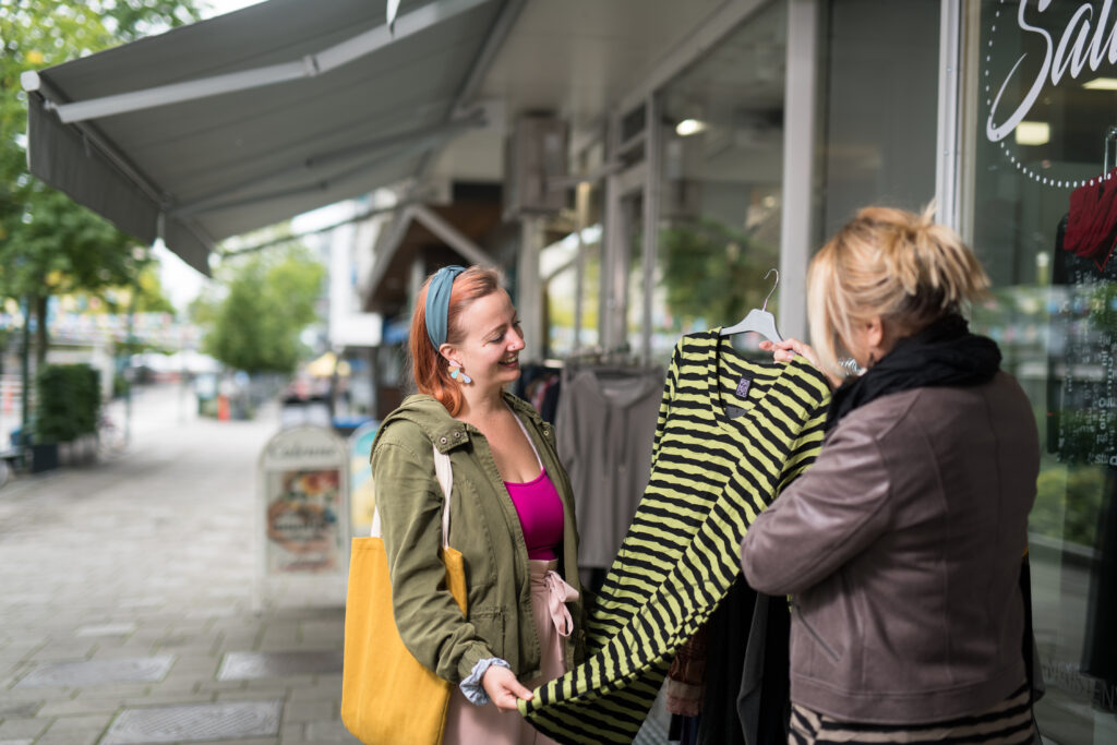 Naiset katsovat vaatemyymälän ulkopuolella vaatetta.