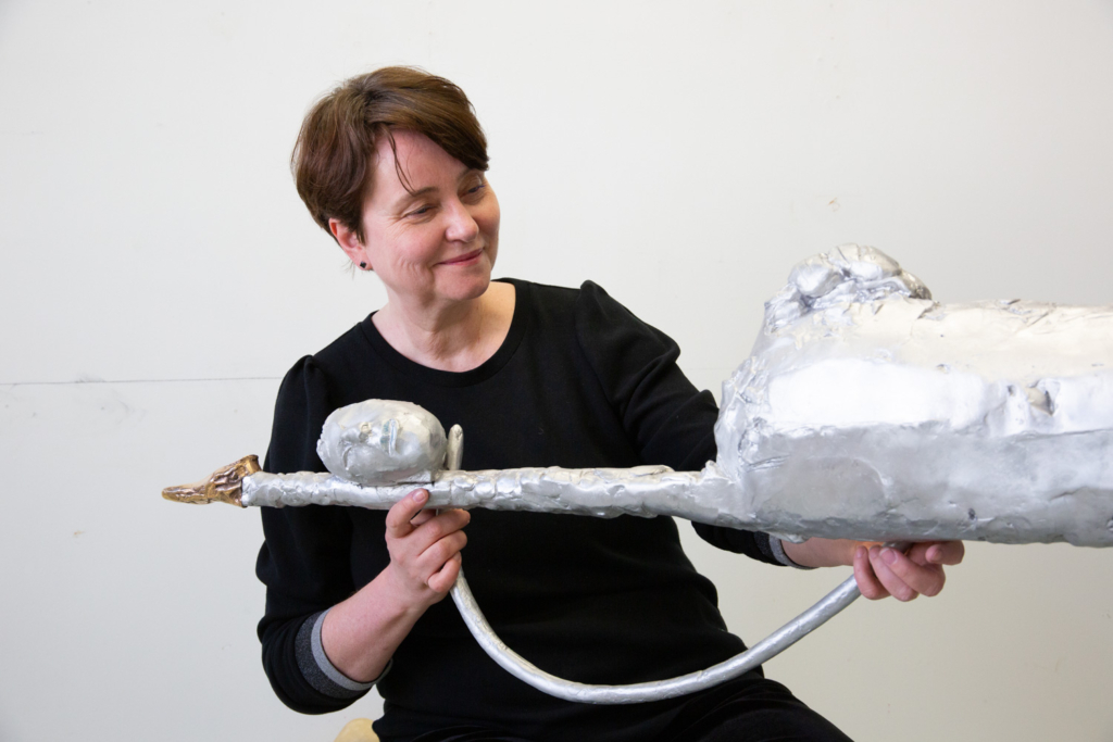 Marjukka Korhonen käsittelee metallinhohtoista teostaan työhuoneella.