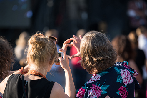 Nuoret katsomassa ja kuvaamassa kännykällä konserttia