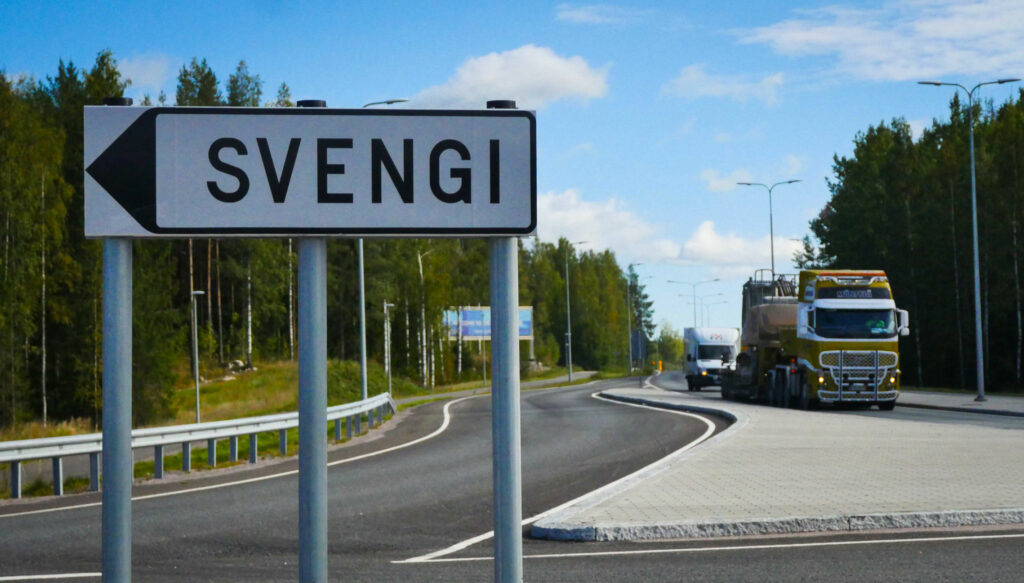 Svengin yritysalueen kyltti, taustalla näkyy rekka, pakettiauto ja metsää.